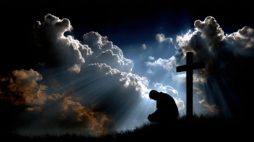 photo man kneeling near cross with very dark storm clouds but light breaking through