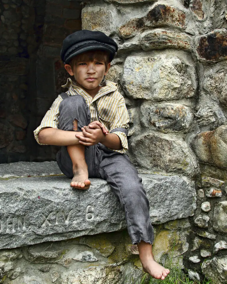 photo of dirty little boy sitting on stone stoop in earlier time