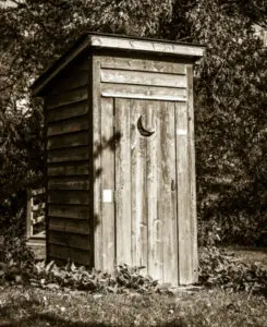 old wooden privy outhouse at edge of woods
